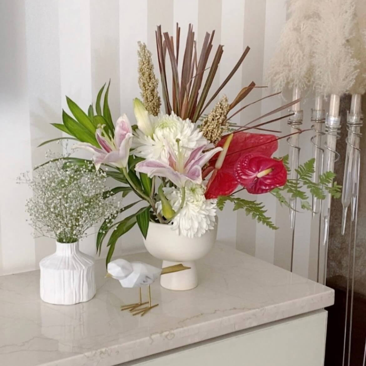 Floral arrangement with white and pink flowers on a surface with a neutral background